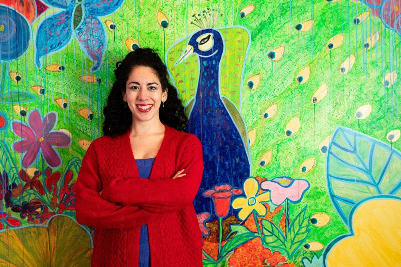 Photo of Christine Sloan Stoddard with her peacock mural by Shawn Inglima.